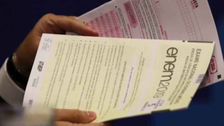 Pessoa segurando 2 cadernos de prova do Enem