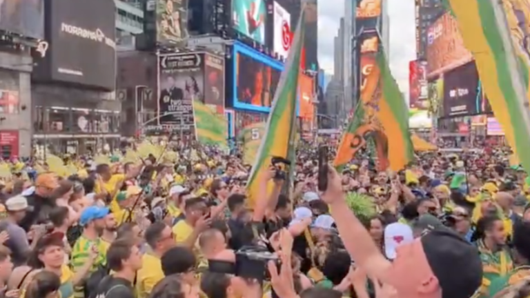 Na imagem, torcedores brasileiros reunidos na Times Square com camisas da seleção e bandeiras